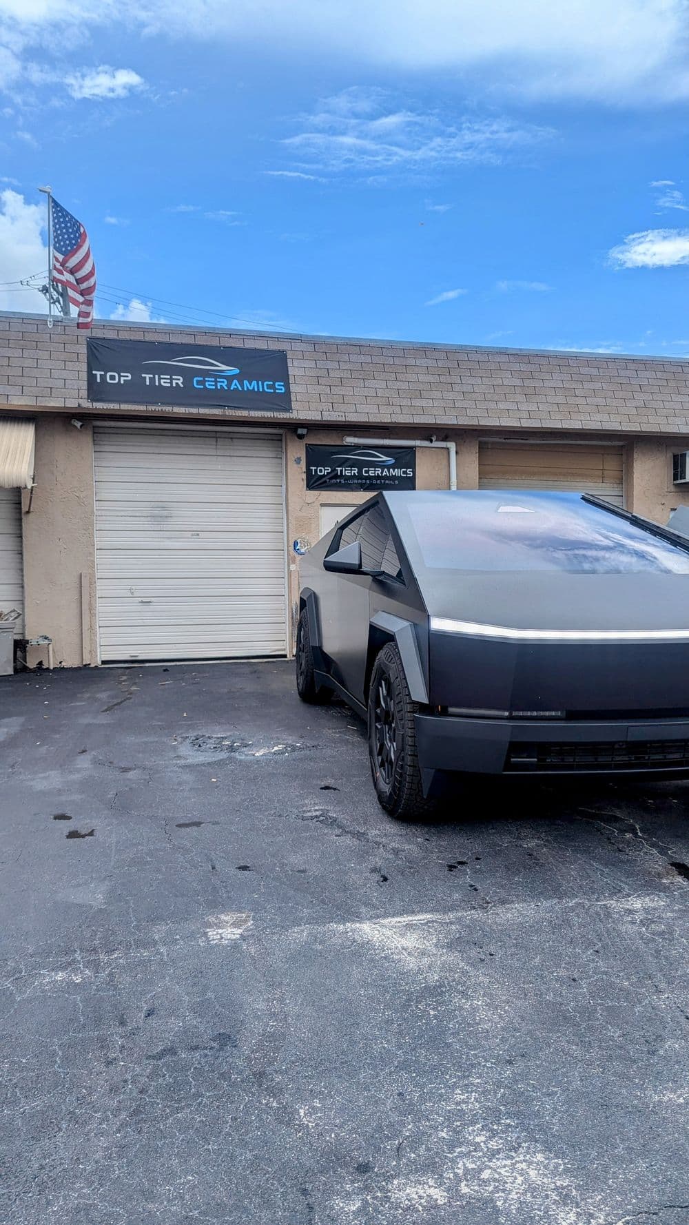 Futuristic vehicle parked in front of "Top Tier Ceramics" shop.